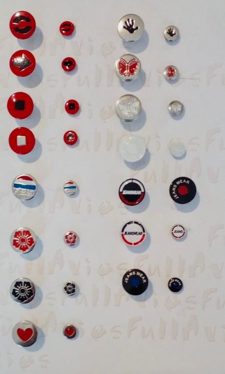 Surtido de botones redondos de colores dispuestos en filas sobre un fondo blanco.