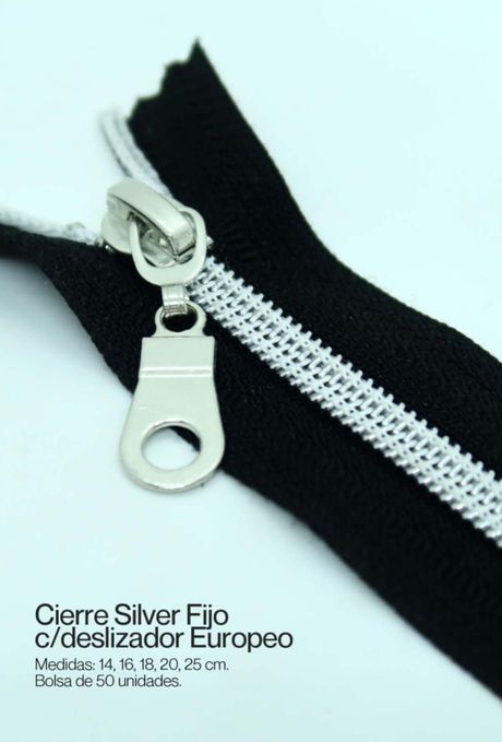 Cremallera plateada sobre tela negra con etiqueta de texto en la esquina.