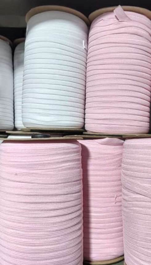 Montones de rollos de tela blanca y rosa doblados, apilados en los estantes de una tienda.