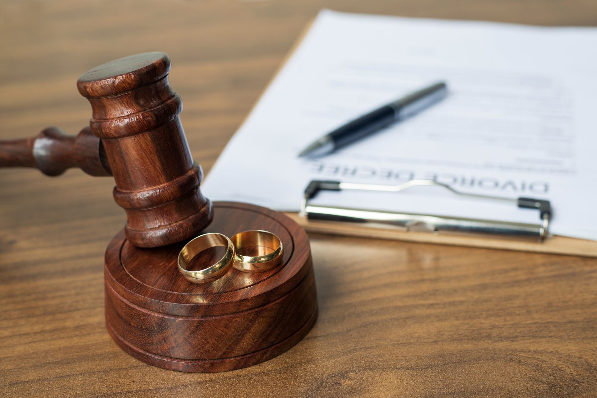 Wooden gavel, wedding rings, and divorce decree document on a desk, signifying a divorce