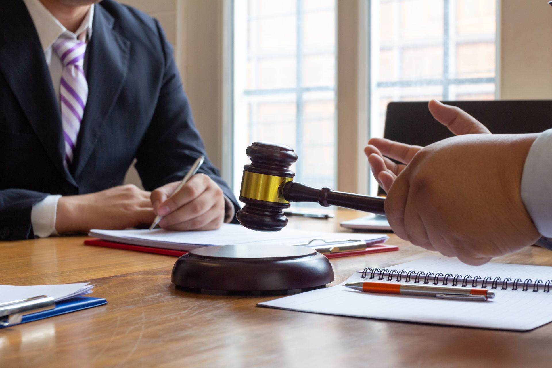 Two lawyers in suits consult over documents at a table