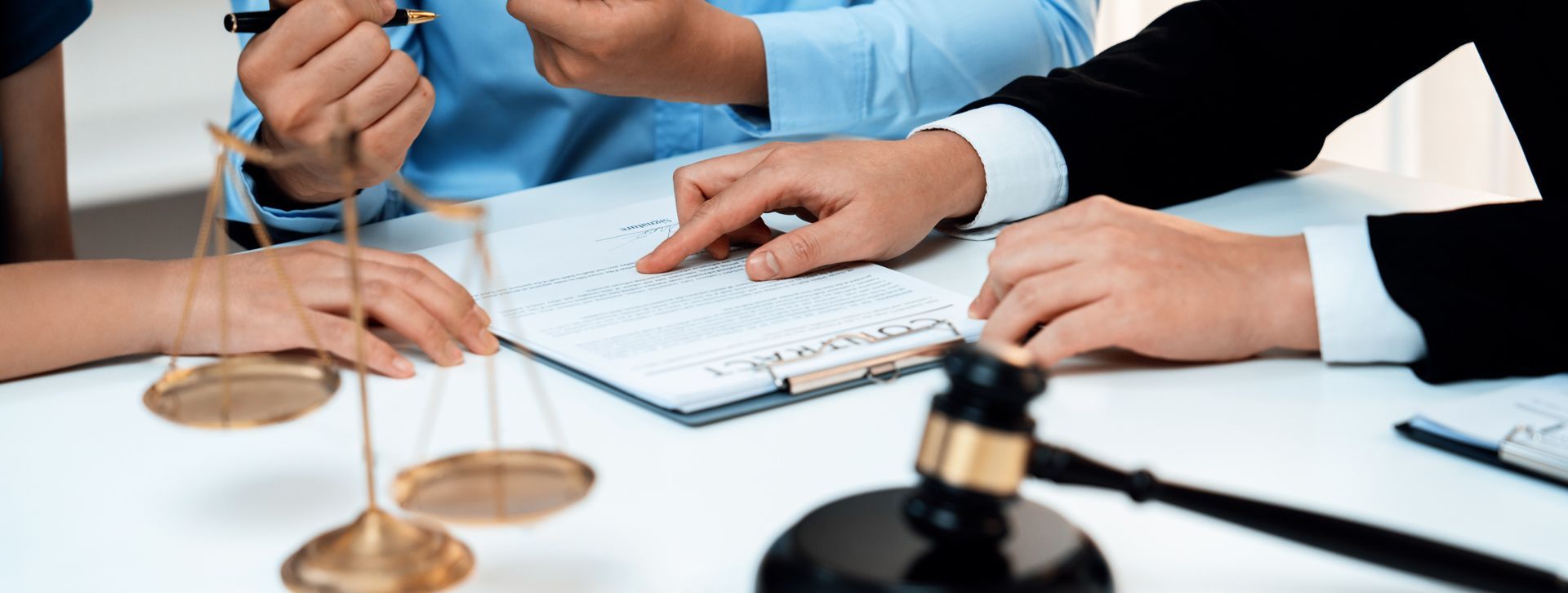 People at a table with a gavel and scale discussing documents