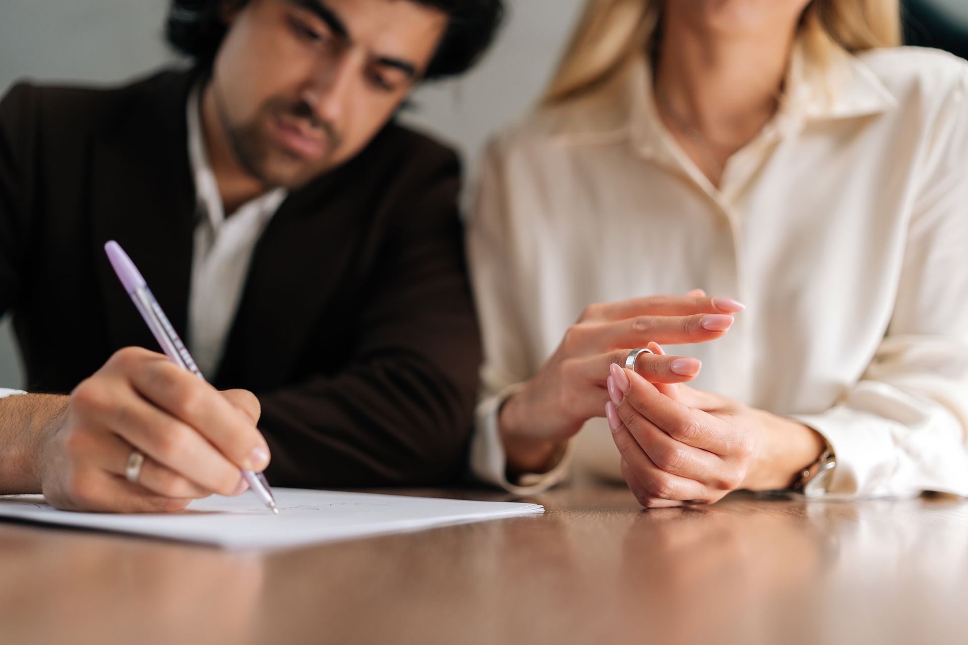 Man signs document; woman removes ring