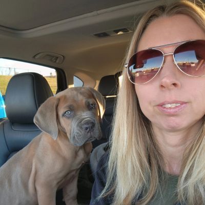 Woman in sunglasses with a puppy in a car.