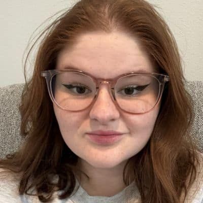 Person with reddish-brown hair wearing glasses with winged eyeliner; looking at the camera.