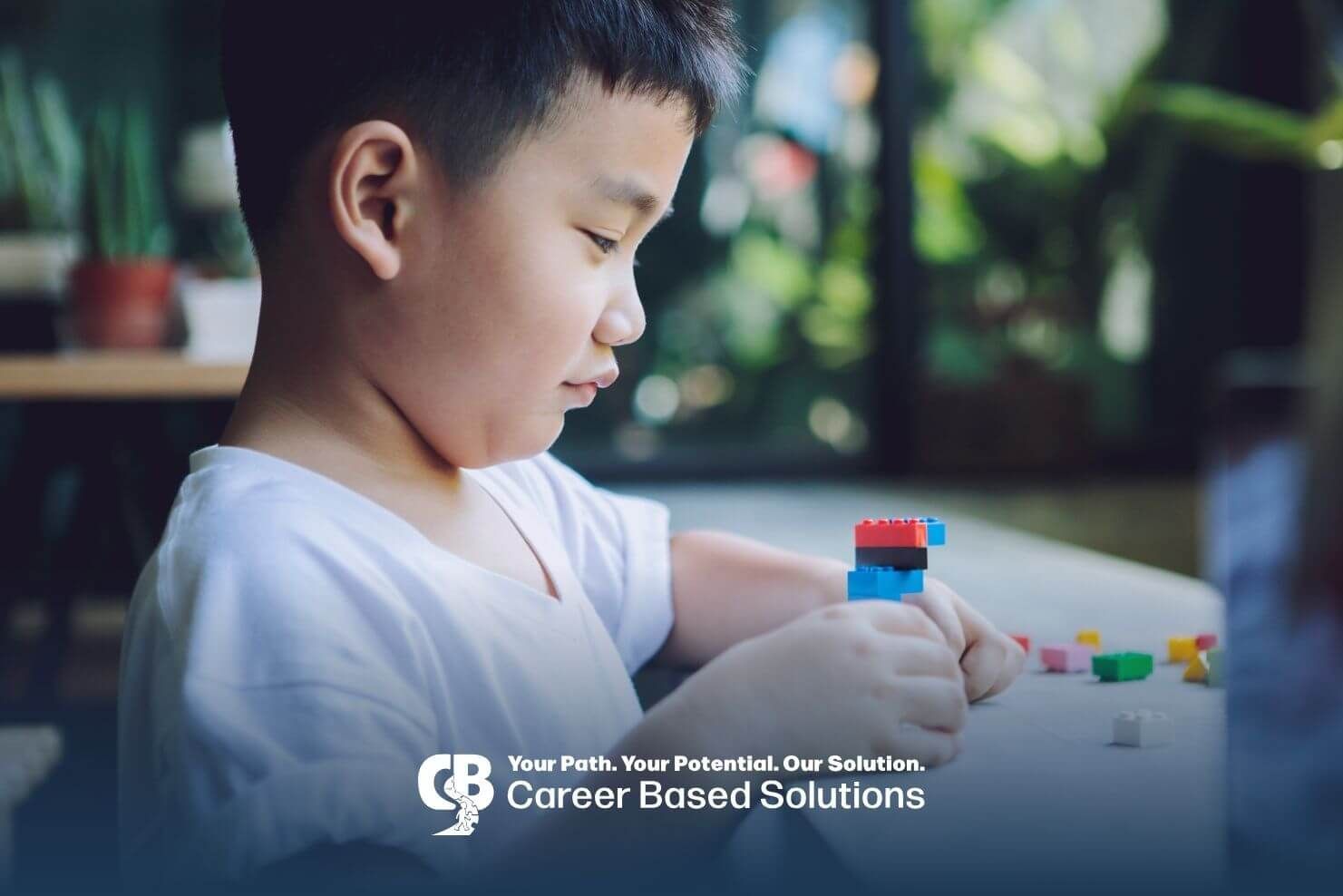 An autistic child concentrating while building colorful blocks at table near window after therapy.