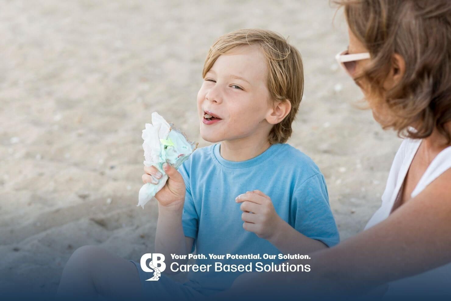 Autistic boy enjoying a snack with a therapist at the beach, encouraging social interaction