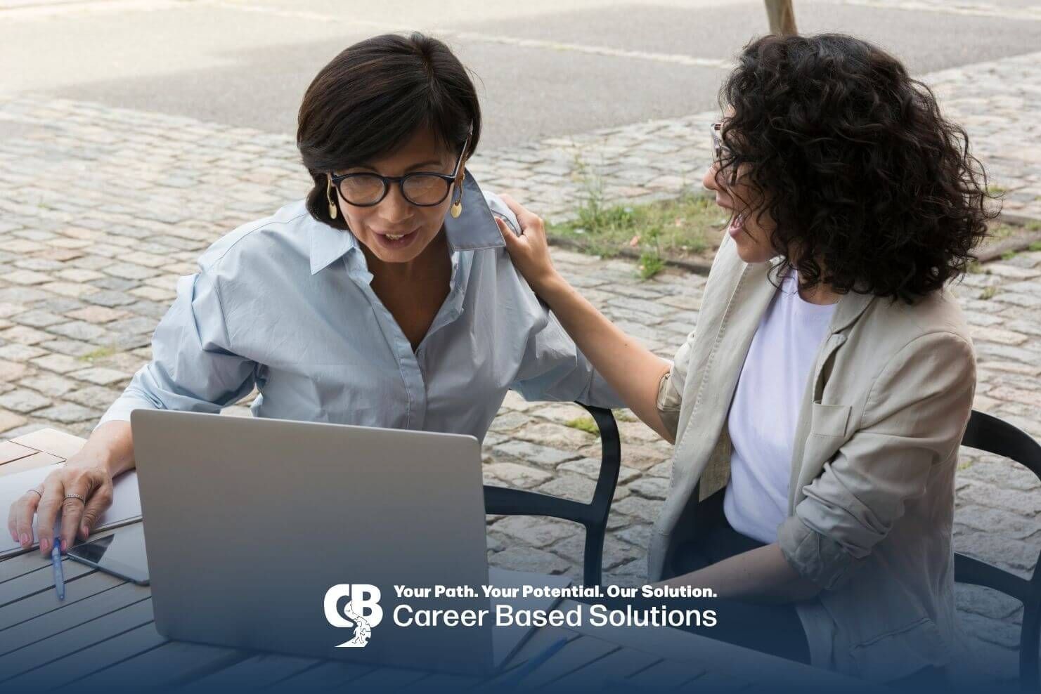 Two ABA therapists reviewing work on a laptop outdoors, discussing RBT ethics and collaboration