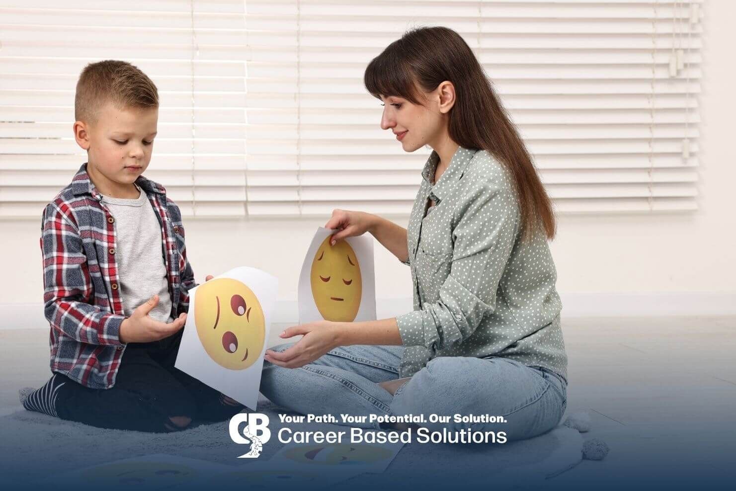 Therapist helping autistic young boy identify emotions using printed emoji cards during session.