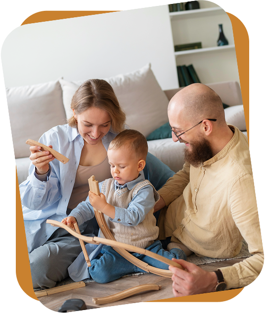 A child sitting on a wooden indoor swing in a room filled with colorful plastic building blocks scattered on the floor.