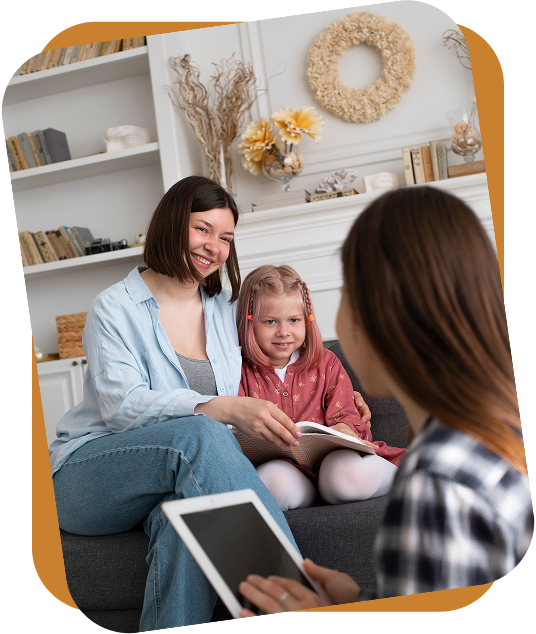 An RBT shows three flashcards featuring clothing items to a child sitting on a rug in a bright room.
