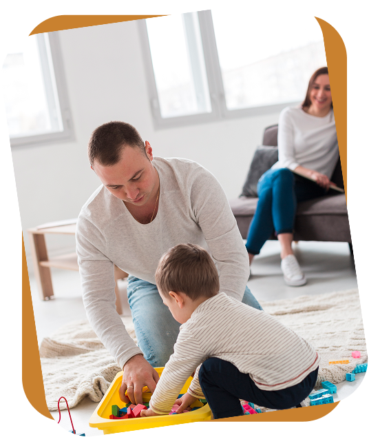An RBT shows three flashcards featuring clothing items to a child sitting on a rug in a bright room.