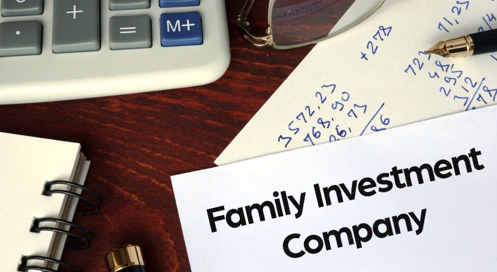 Image of financial notes, a calculator, pen and some glasses, with Family Investment Company in bold letters
