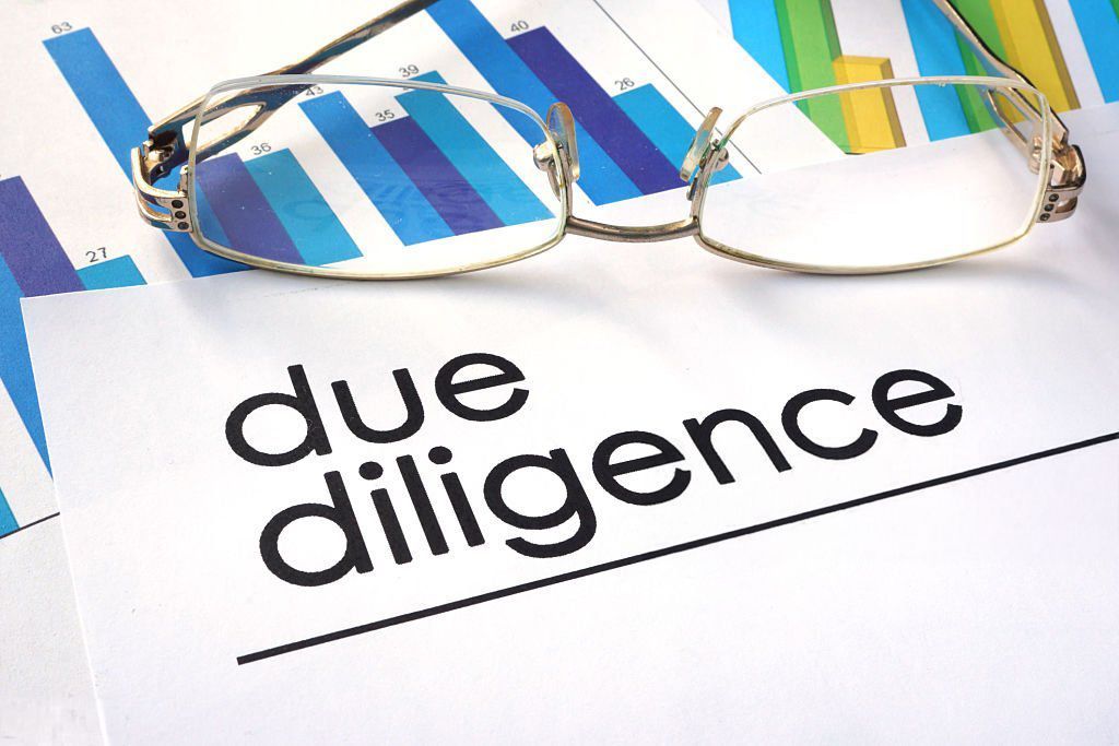 A pair of glasses rests on a piece of paper that says due diligence