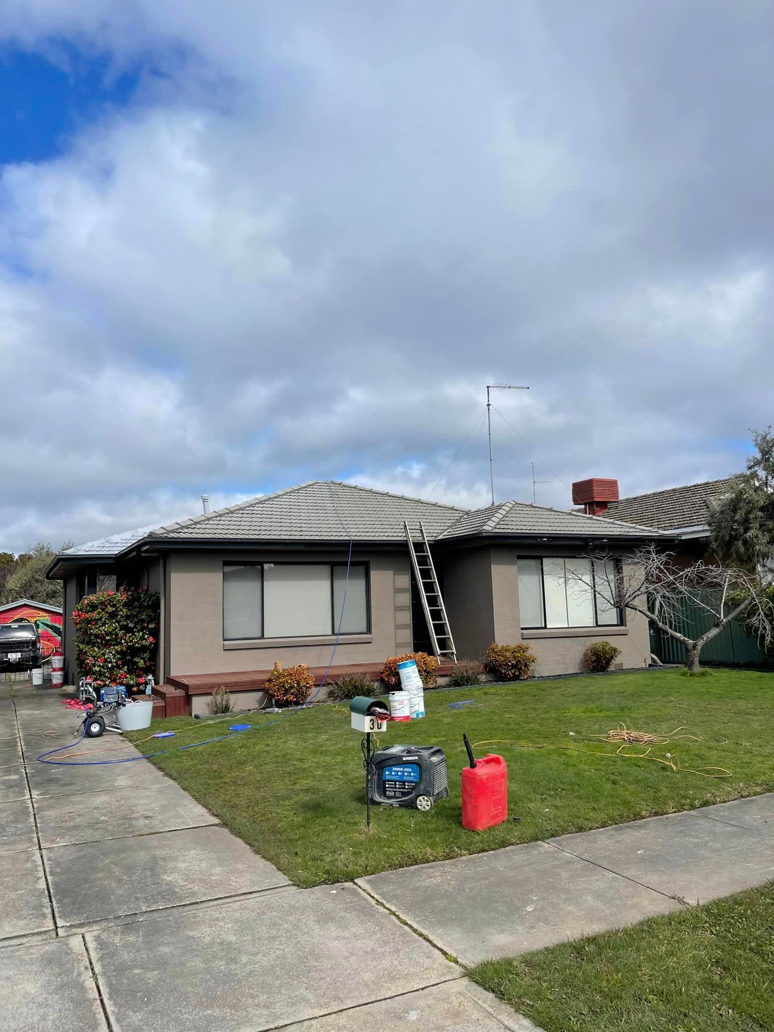 A house with a ladder on the roof is being painted