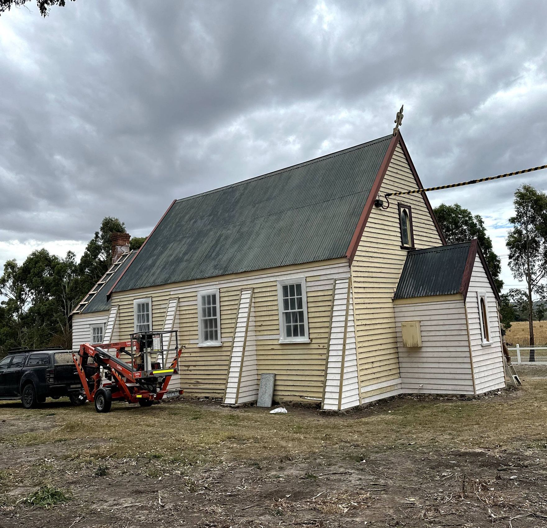 A house with a ladder on the roof is being painted