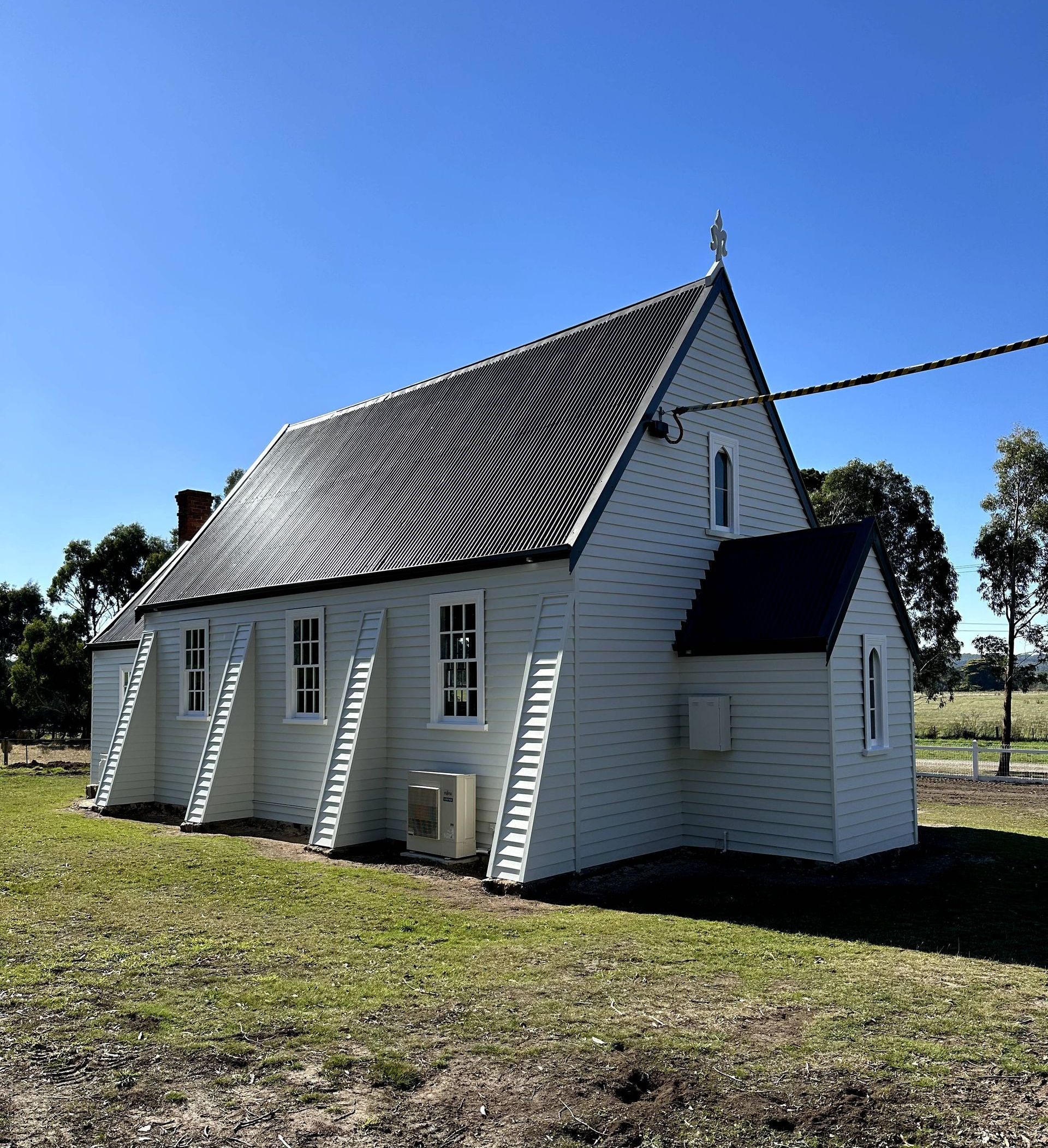 A house with a ladder on the roof and a lawn in front of it