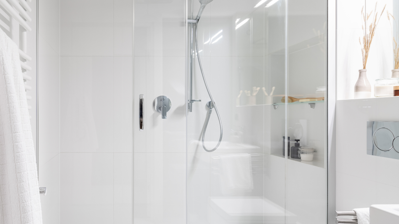 A bathroom with a shower , toilet , sink and mirror.
