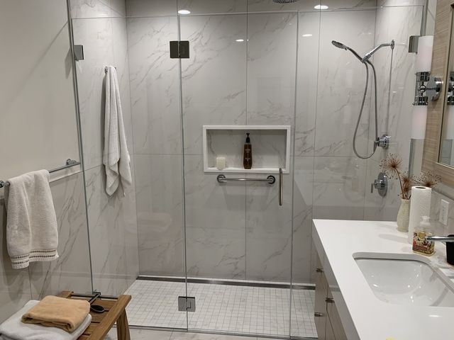 A bathroom with a walk in shower and a sink.