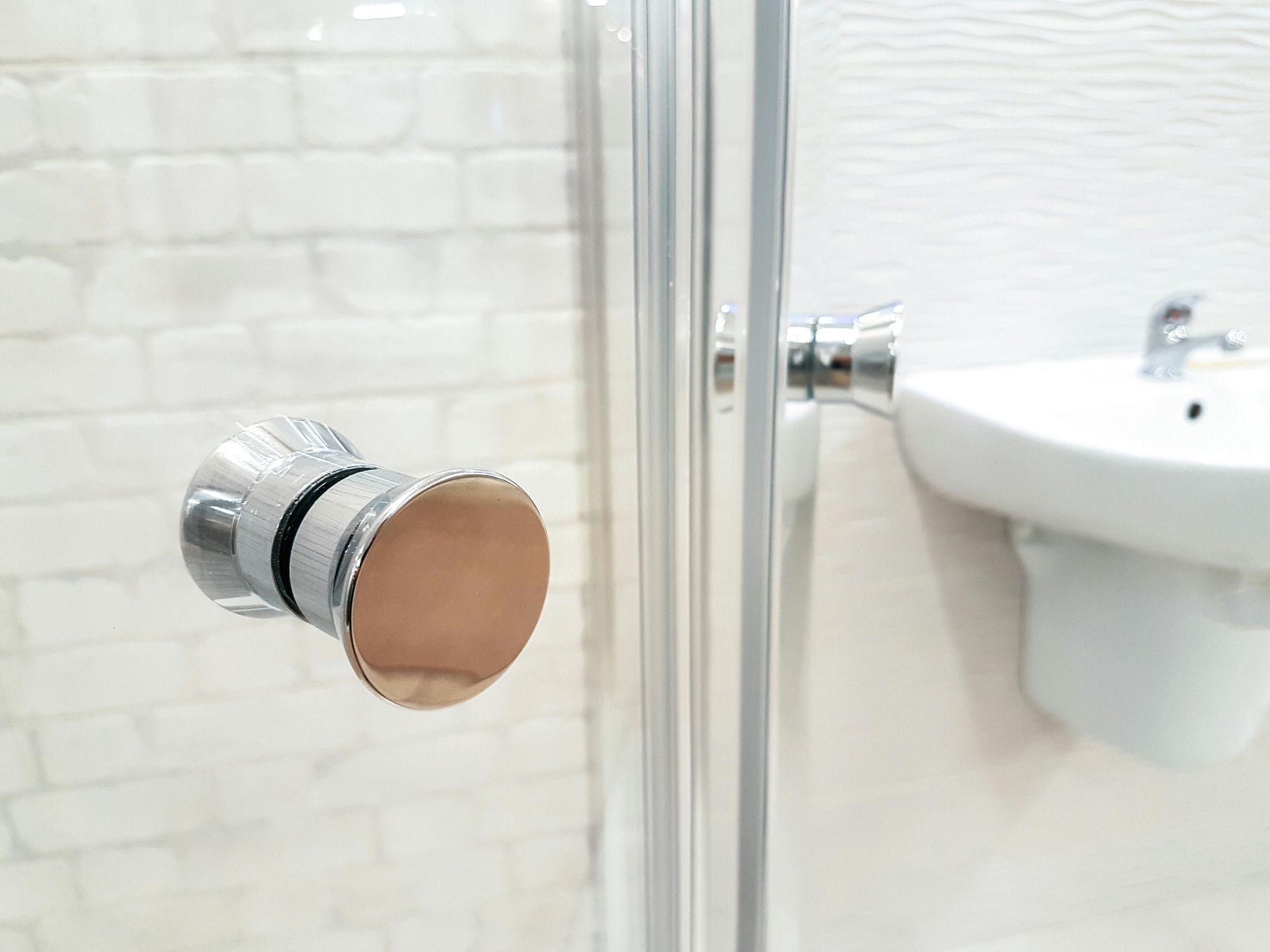 A close up of a shower door in a bathroom next to a sink.