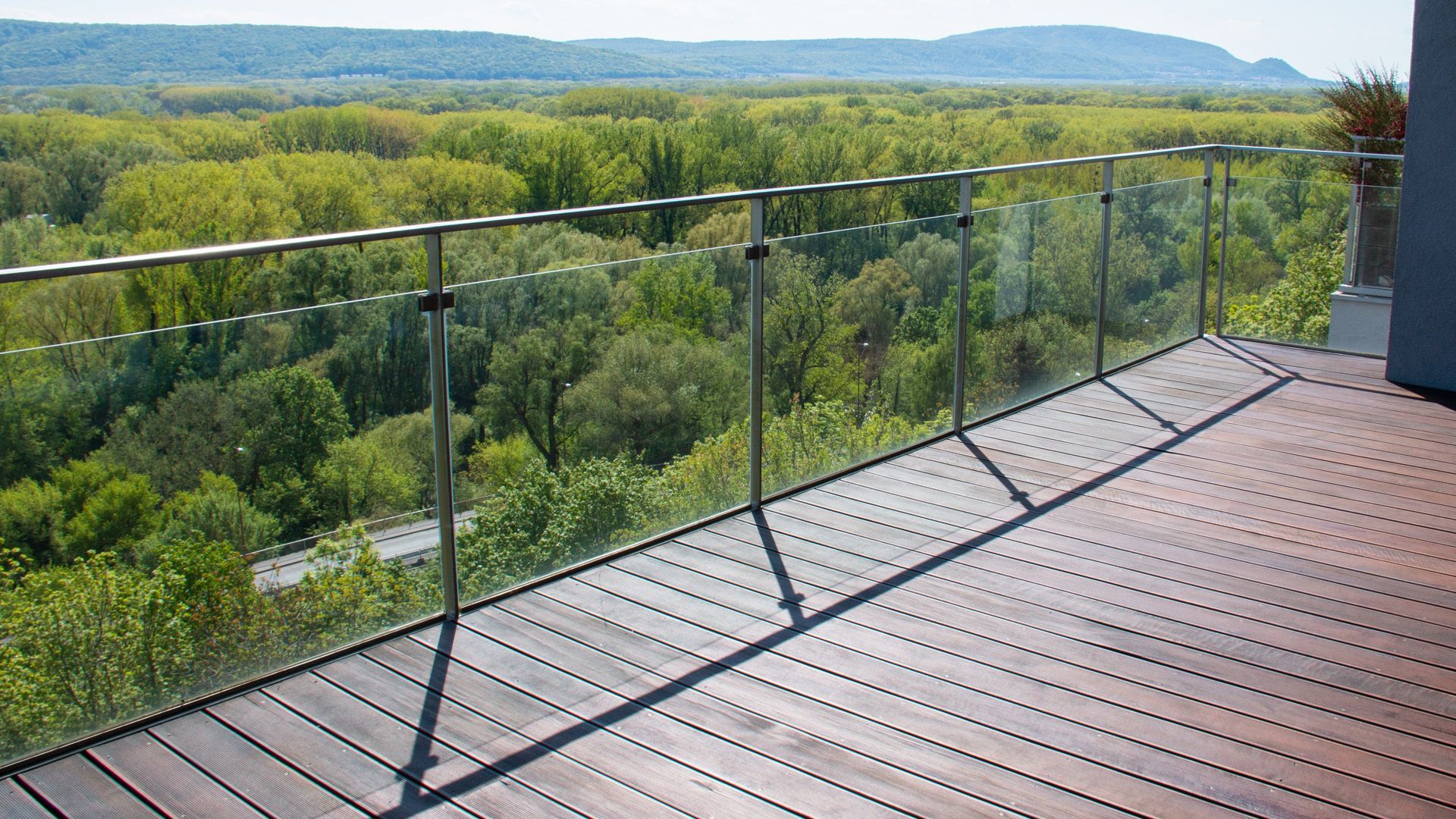 a wooden deck with a glass railing overlooking a forest