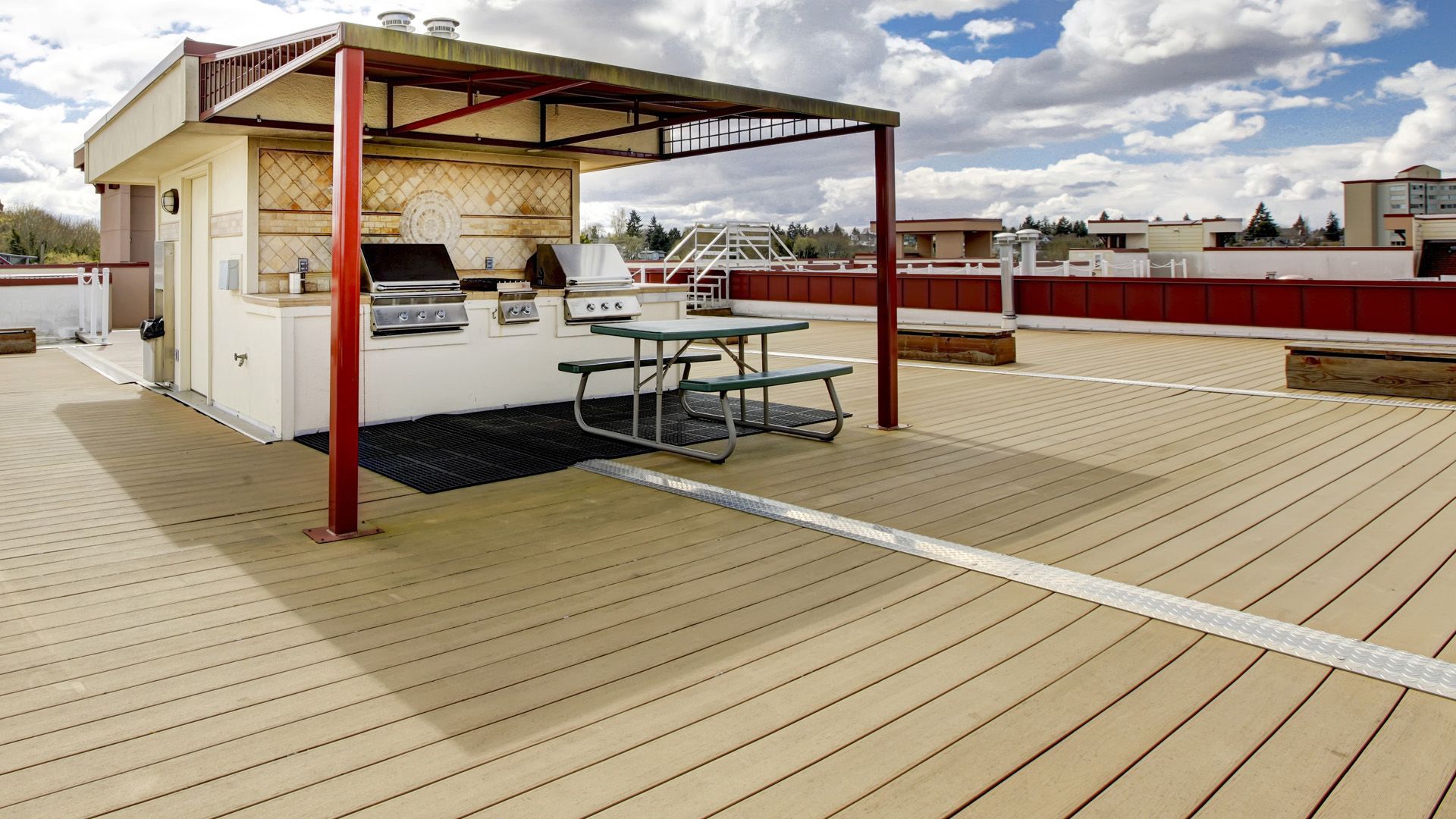 a rooftop deck with a grill and picnic tables