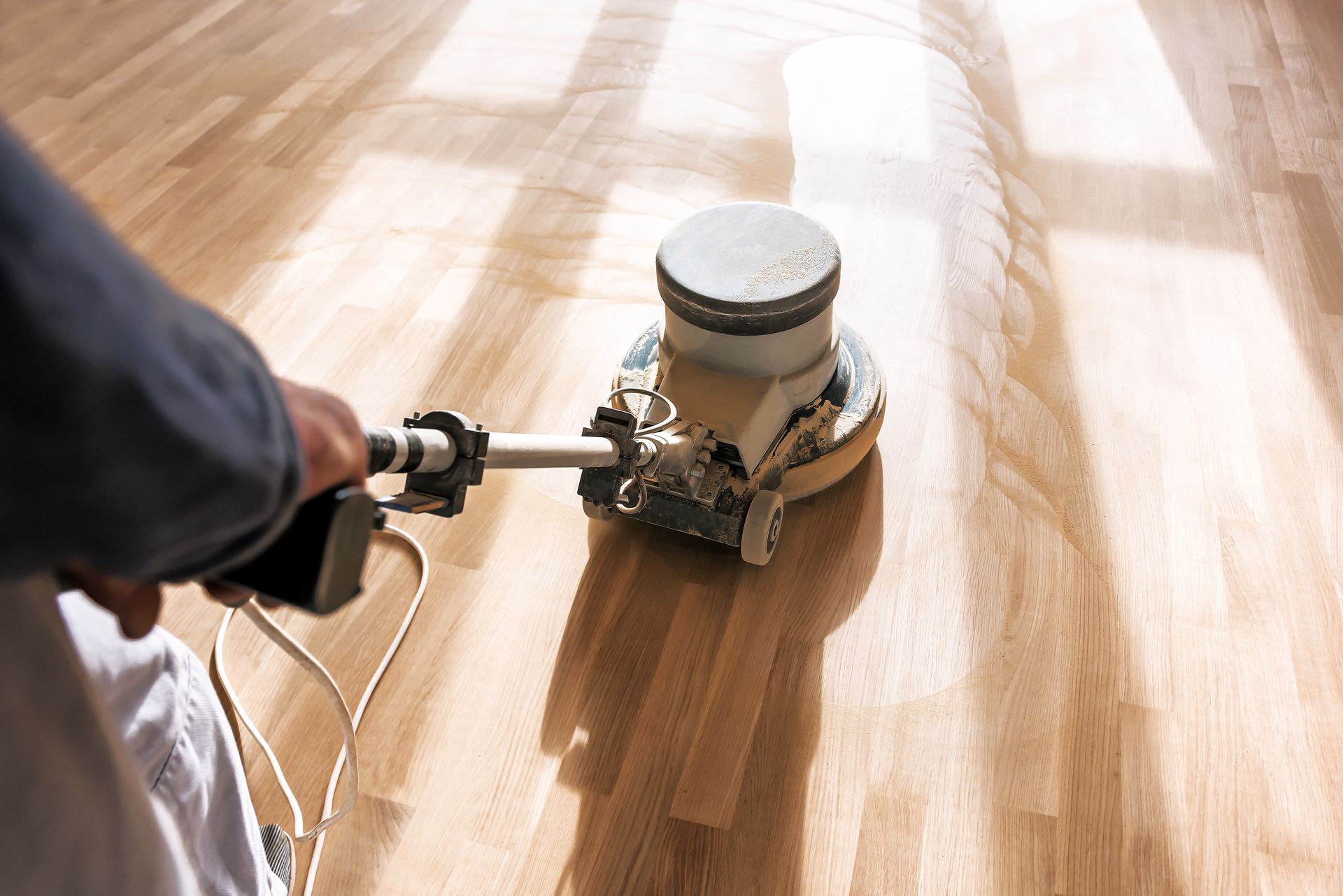 Top view of a worker polishing a hardwood floor with a polishing machine.