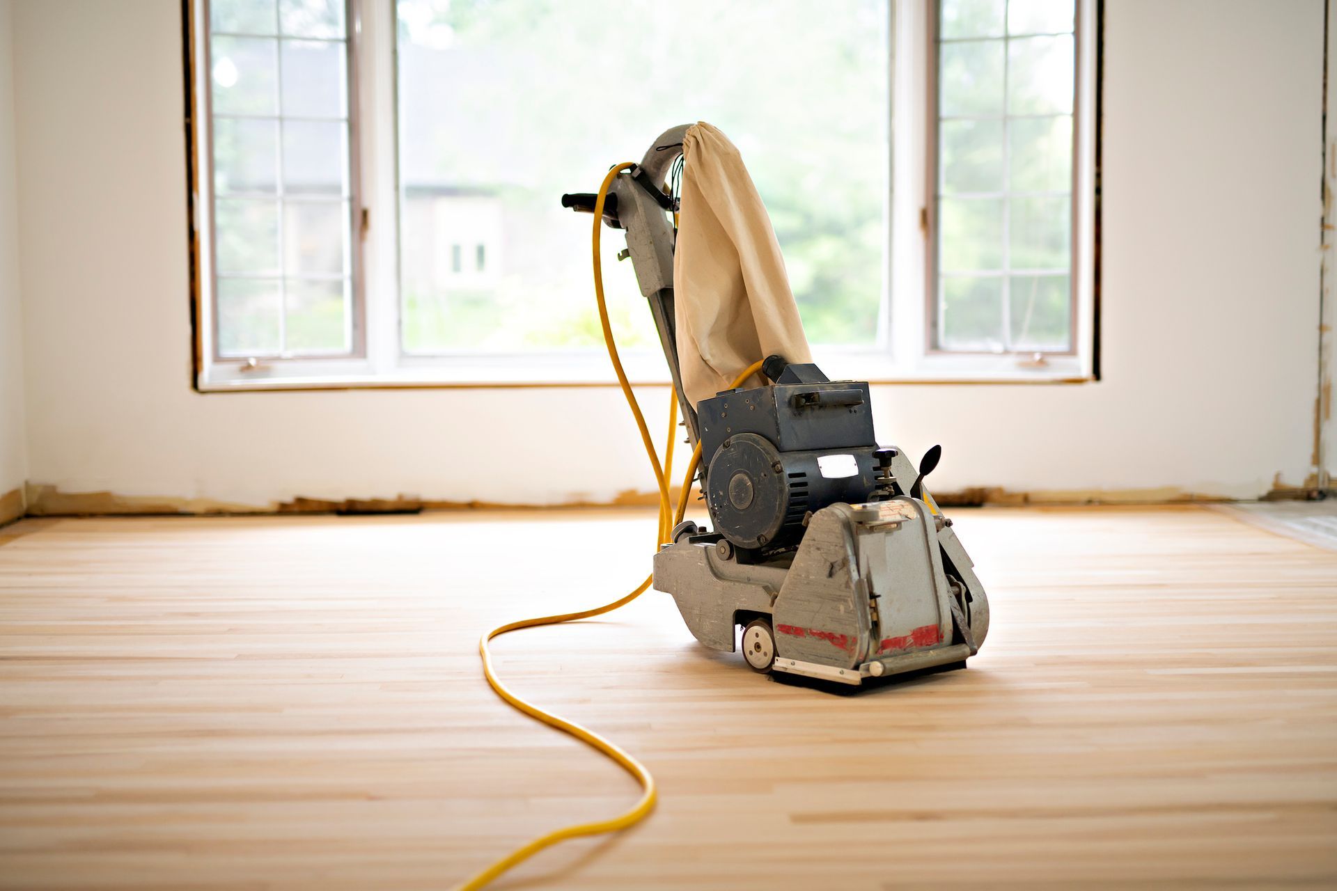 A machine is sitting on a wooden floor in an empty room.