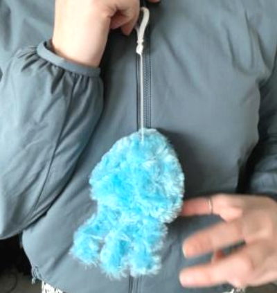 A rainbow colored pop it in the shape of a cupcake on a blue background.