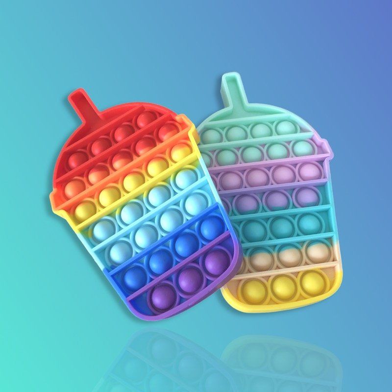 Two rainbow colored pop it fidget toys are sitting on top of each other on a blue surface.