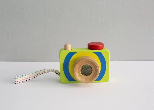 A wooden toy camera is sitting on a white table.