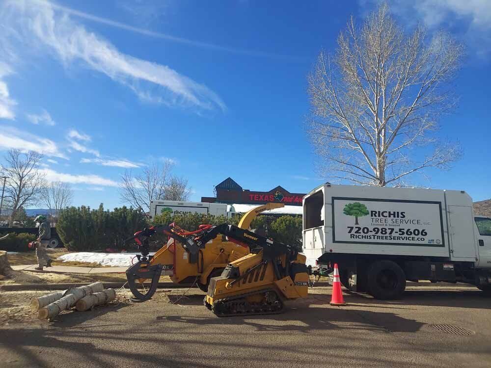 A tree chipper is parked next to a truck in a parking lot.