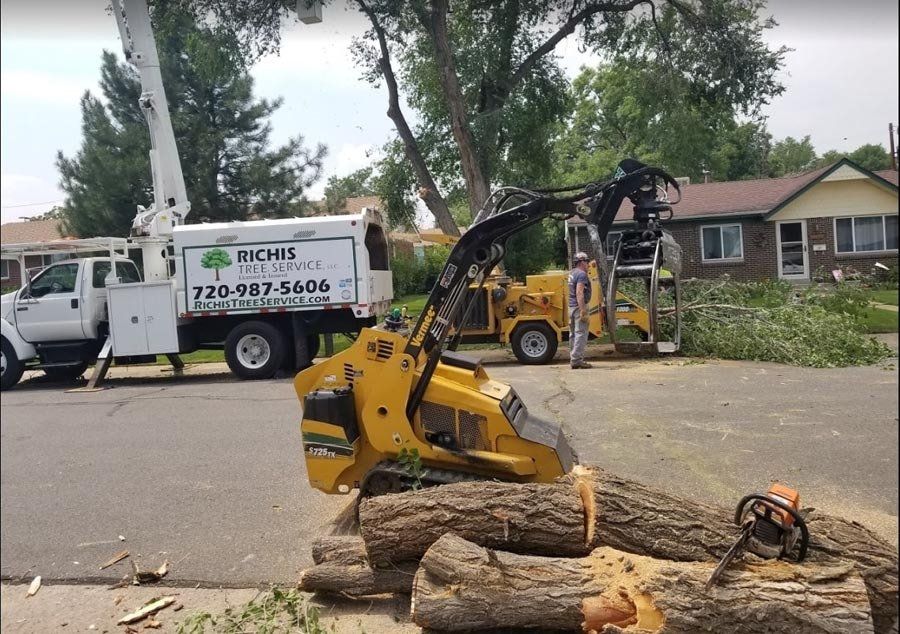 A tree chipper is sitting on a pile of logs next to a truck.