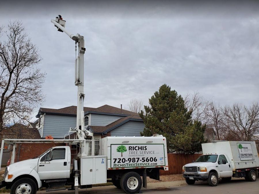 A white truck with a crane on the back is parked in front of a house.