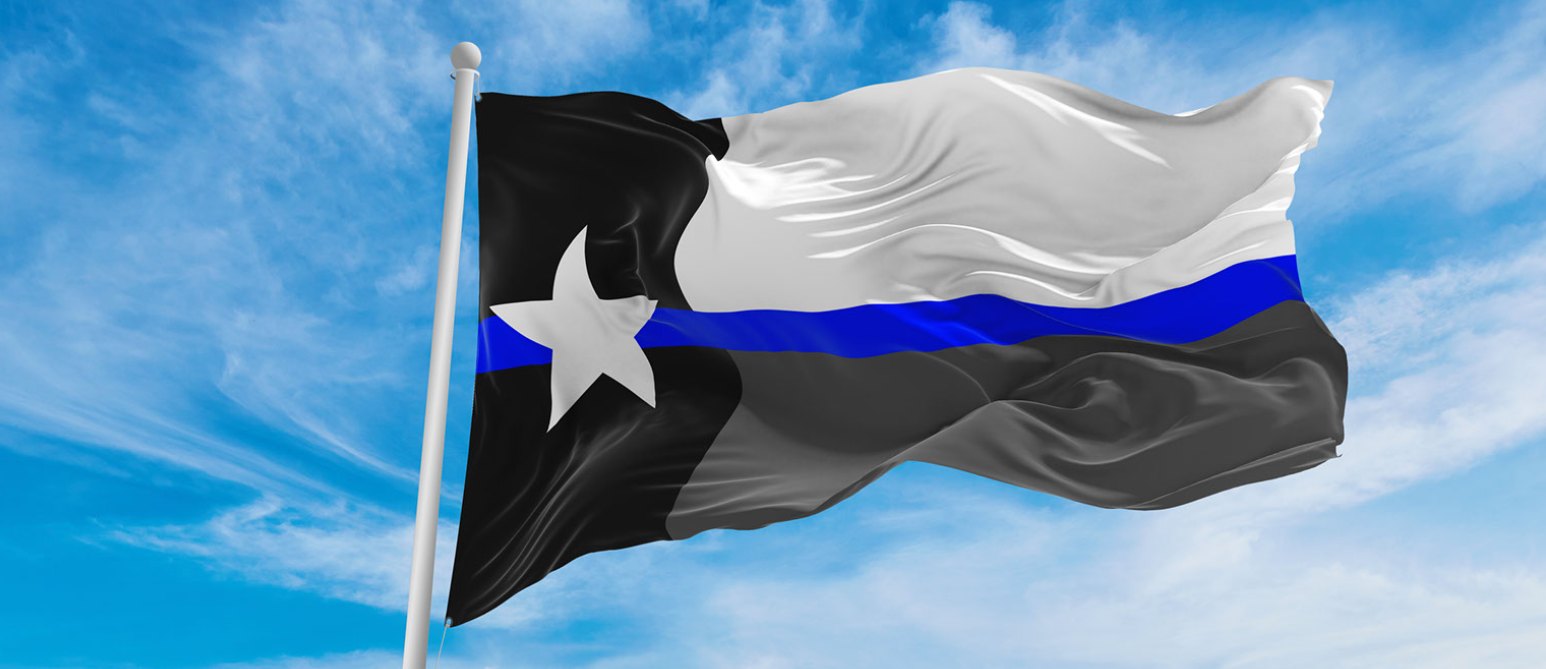 A black , white and blue flag with a star on it is waving in the wind.