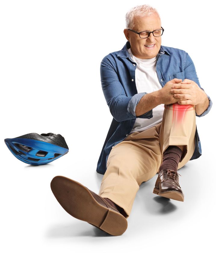 Uomo anziano con dolore al ginocchio, seduto sul pavimento, che si tiene il ginocchio, casco nelle vicinanze.