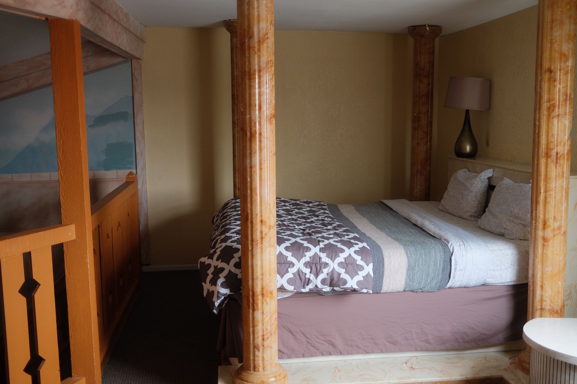 There is a bed in the middle of the room with wooden pillars.