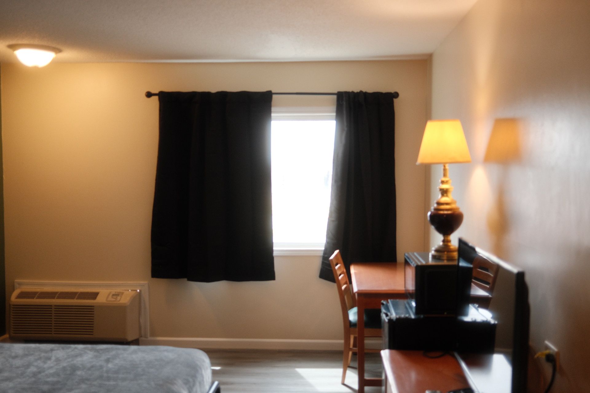 A hotel room with a bed a table and a lamp
