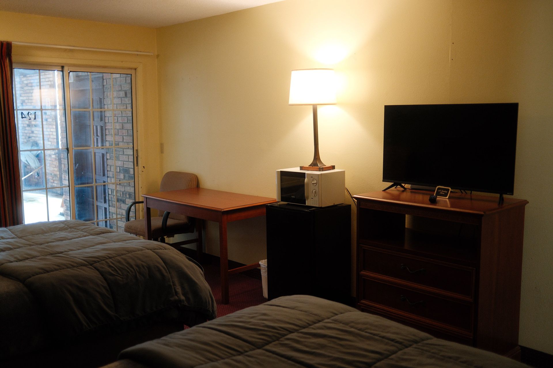 A hotel room with two beds , a desk , a television and a microwave.