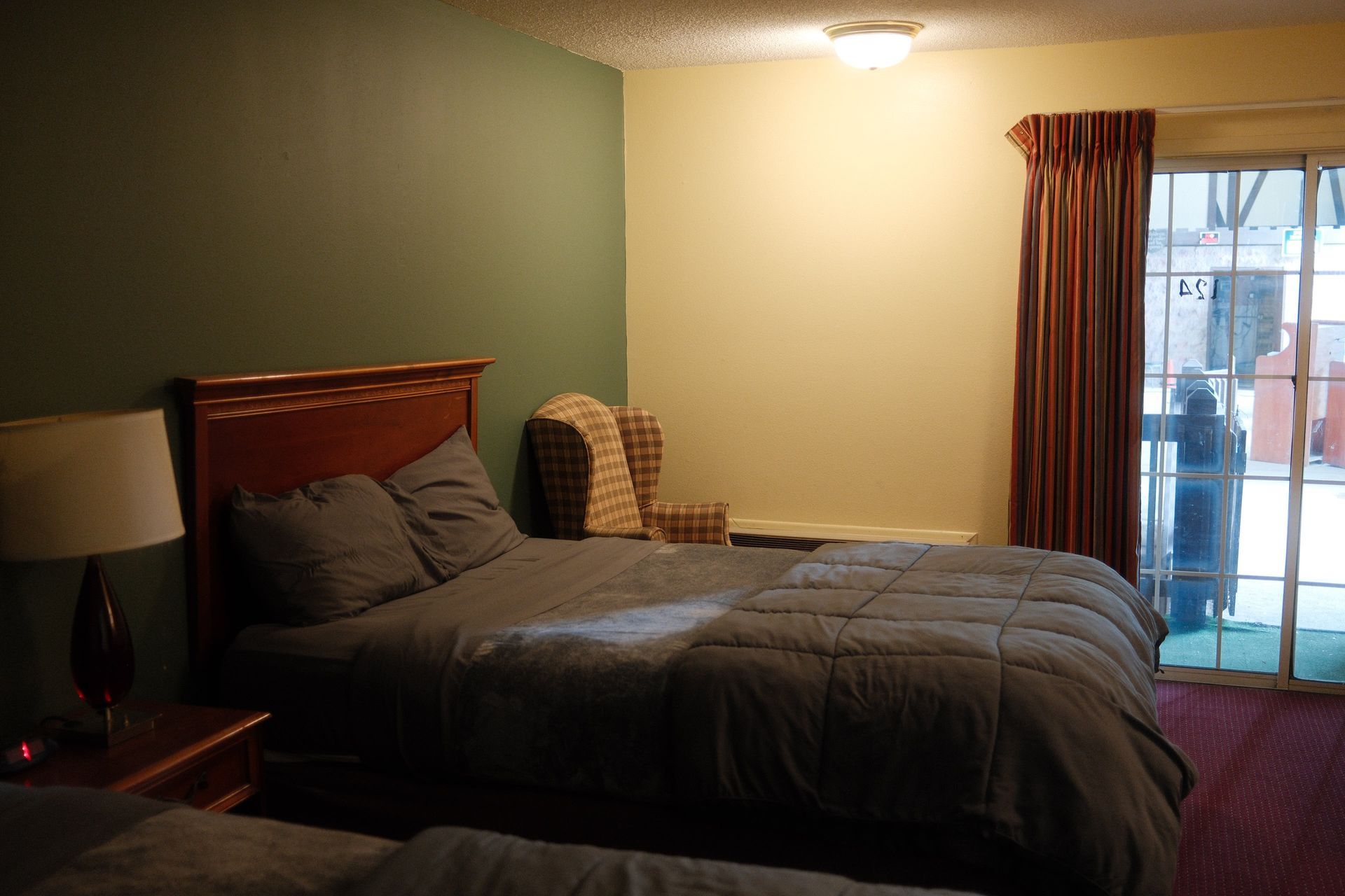 A hotel room with two beds and a sliding glass door.