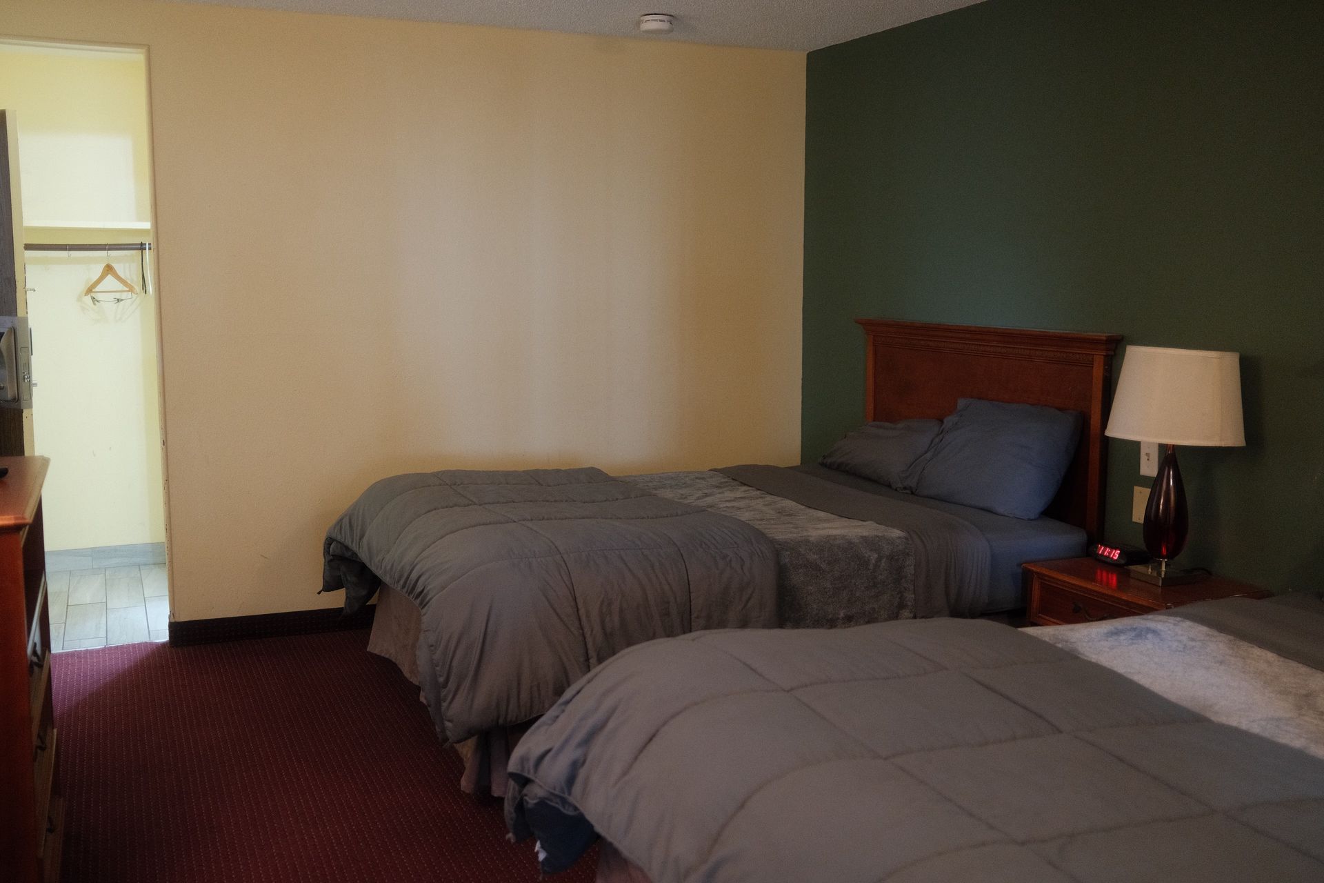 A hotel room with two beds and a lamp.