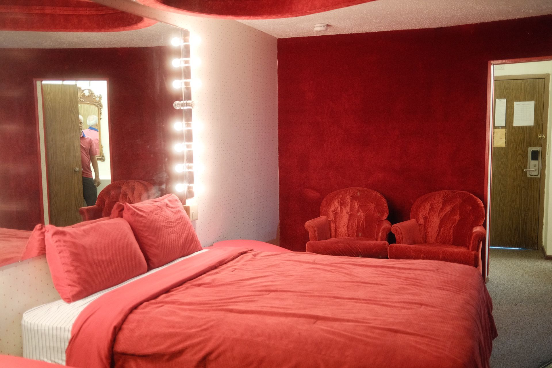 A hotel room with a red bed and chairs