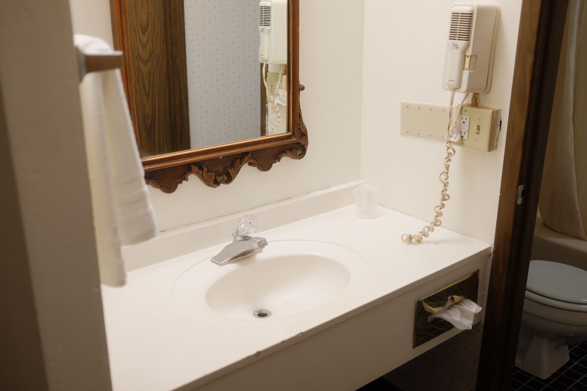 A bathroom with a sink , mirror and hair dryer.