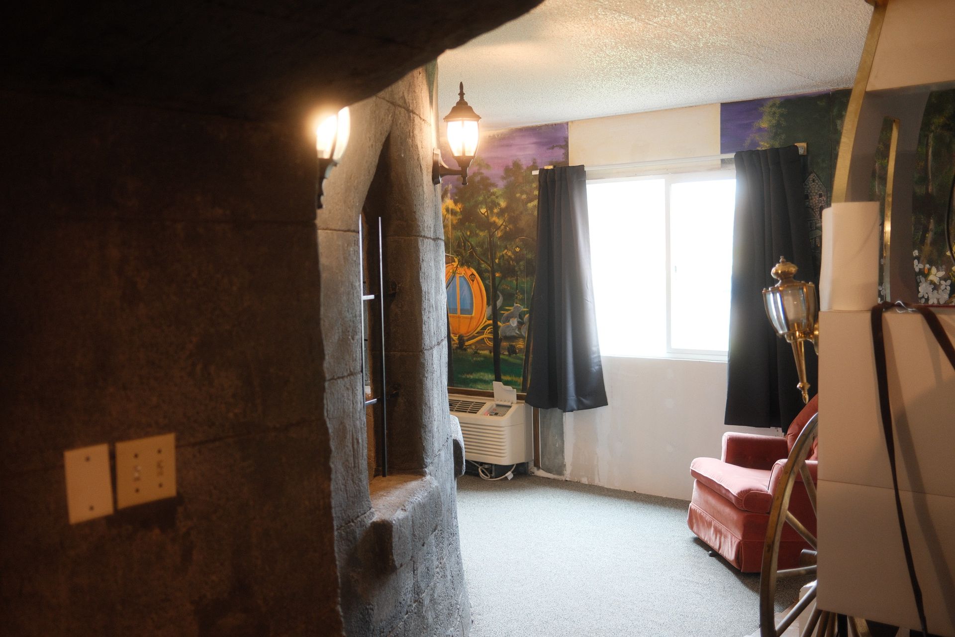 A living room with a red chair and a painting on the wall