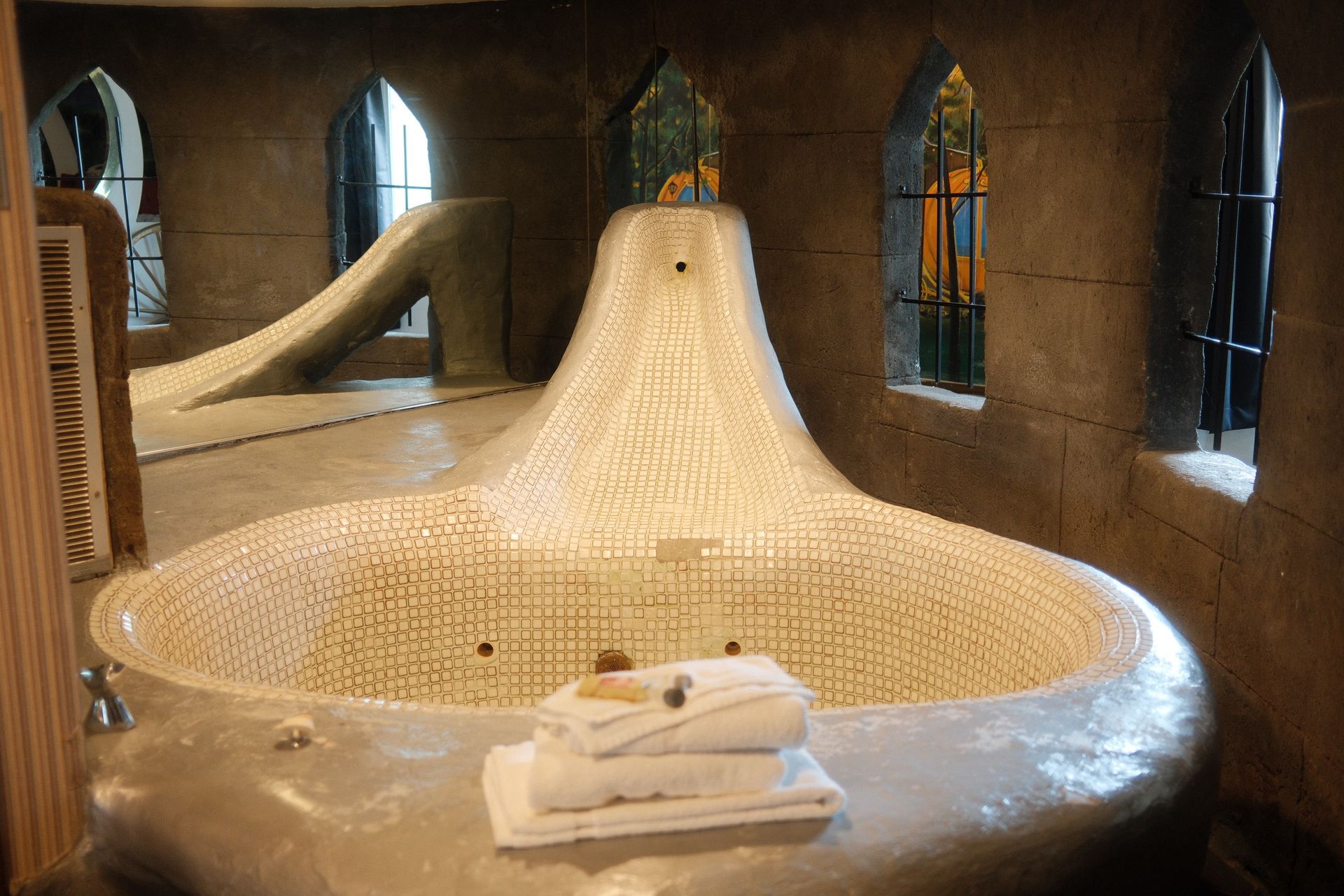 A large bathtub with towels stacked on top of it in a bathroom.