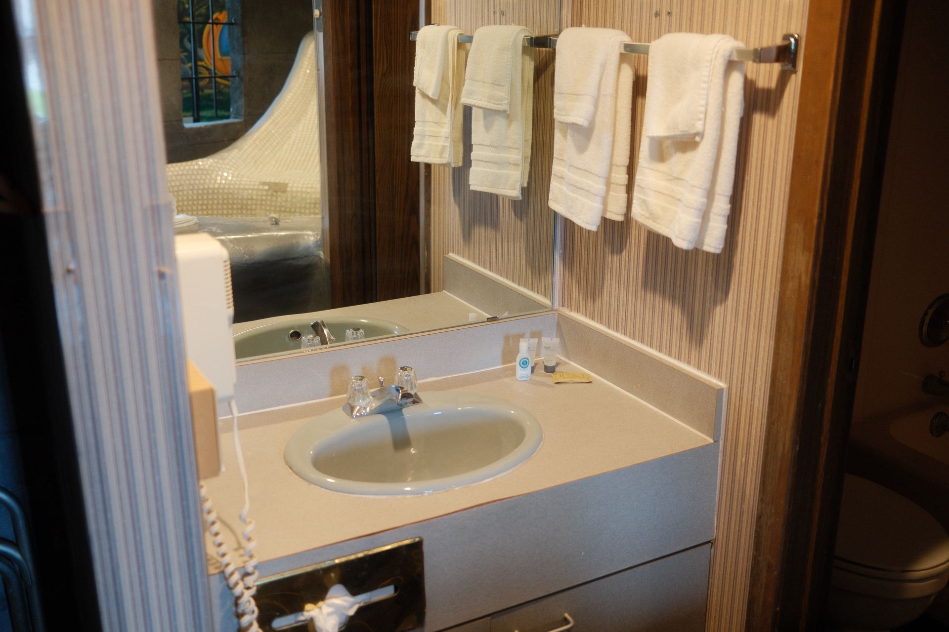 A bathroom with a sink , mirror and towels hanging on the wall.