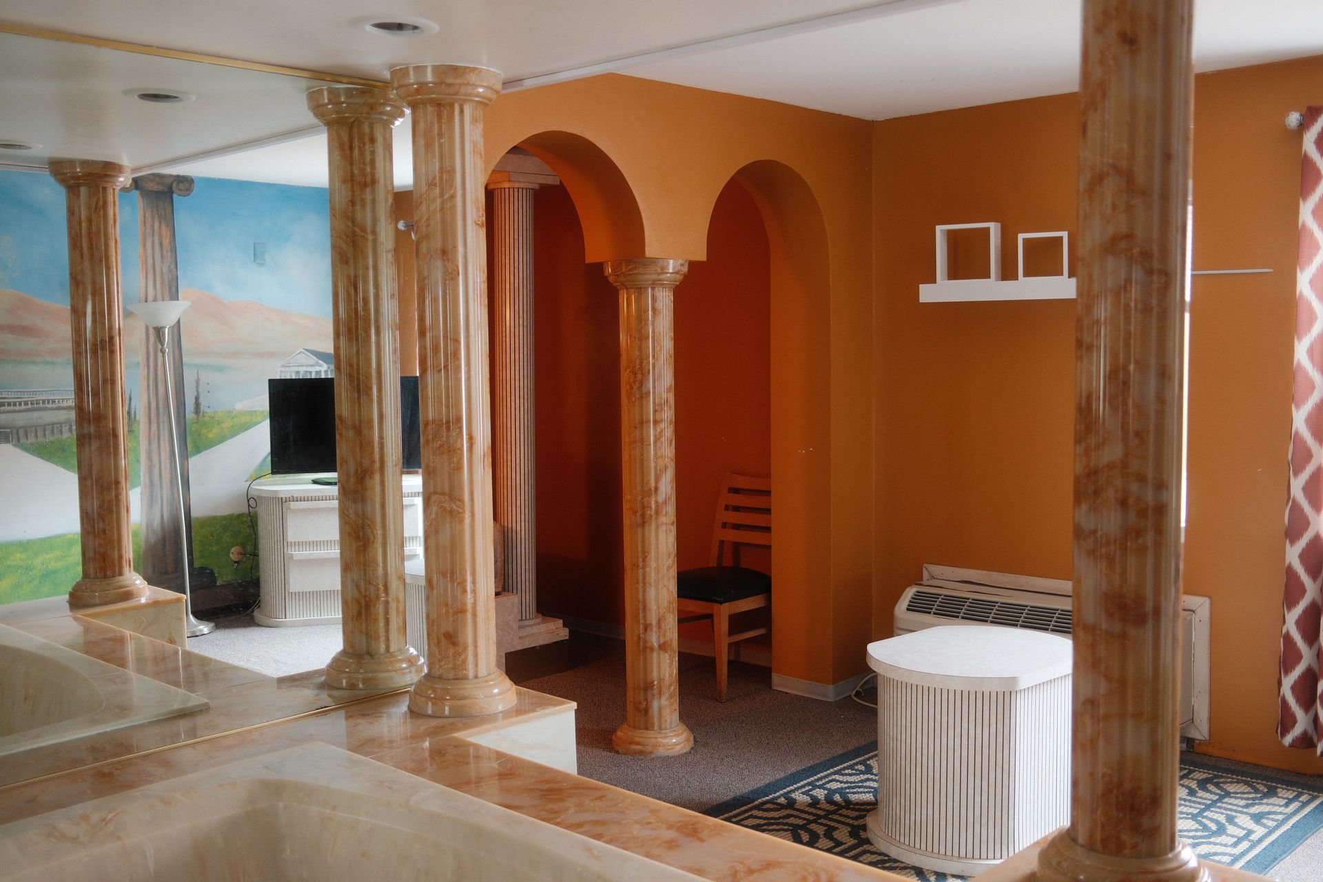 A living room with columns and a painting on the wall