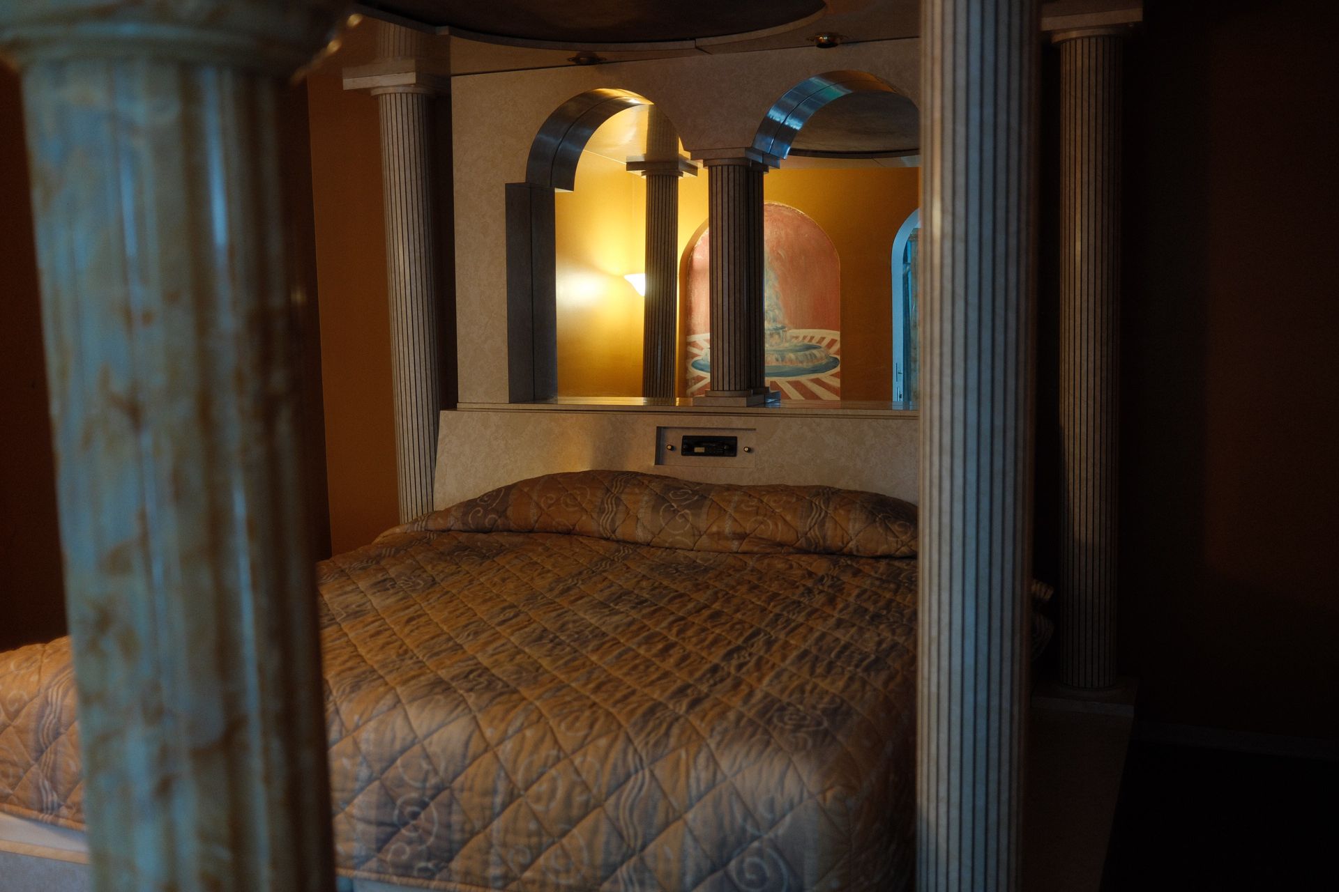 A bed in a hotel room with columns and arches