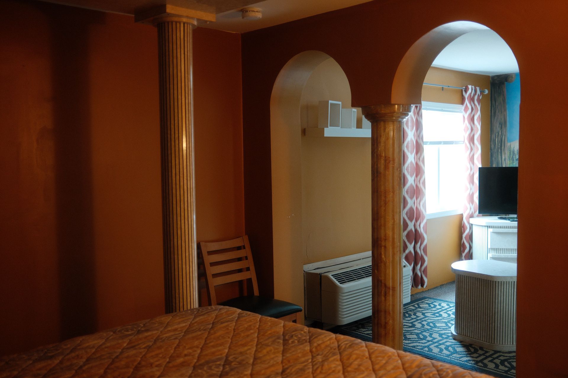 A bedroom with a bed a chair and a television