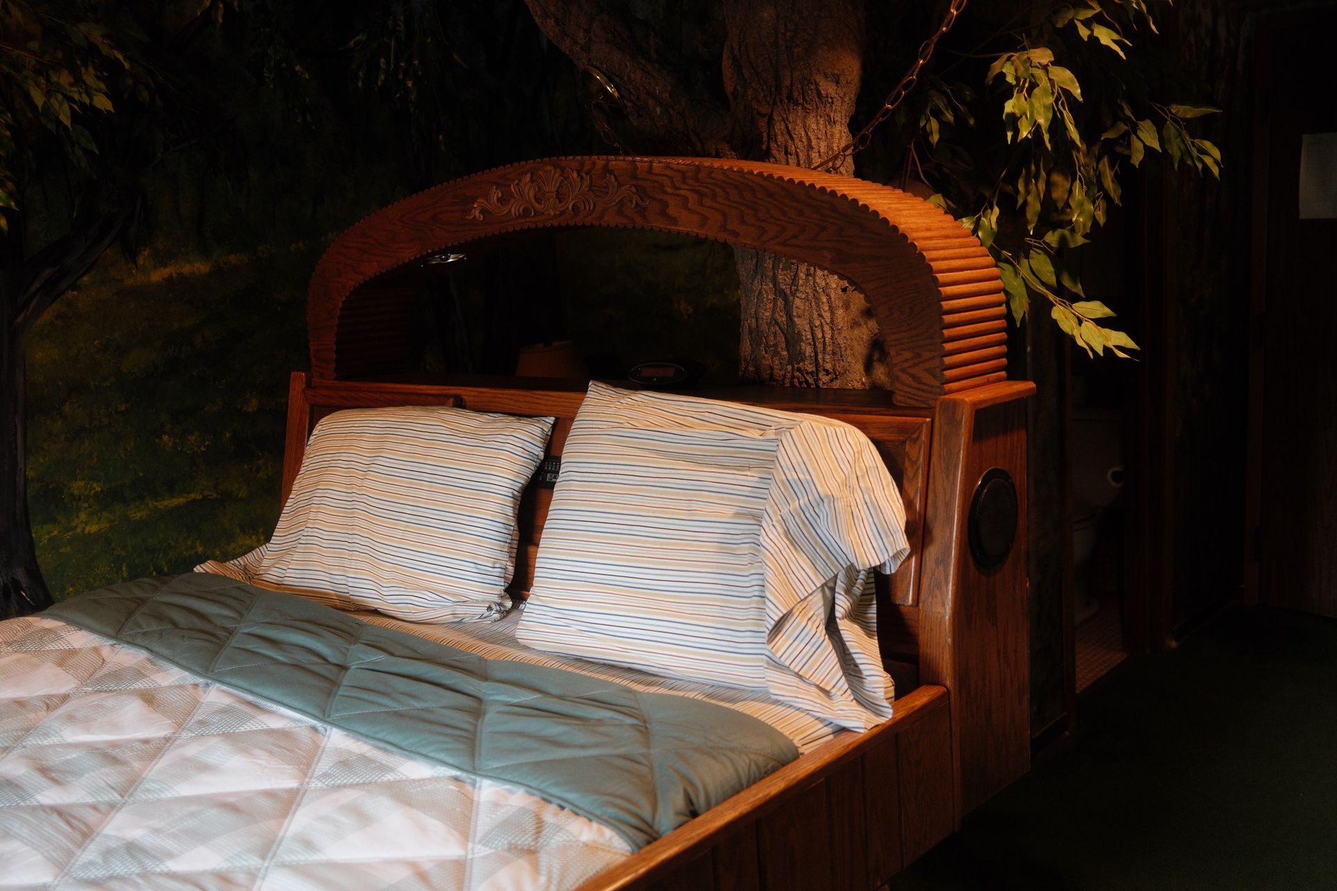 A bed with a wooden headboard and pillows in a dark room